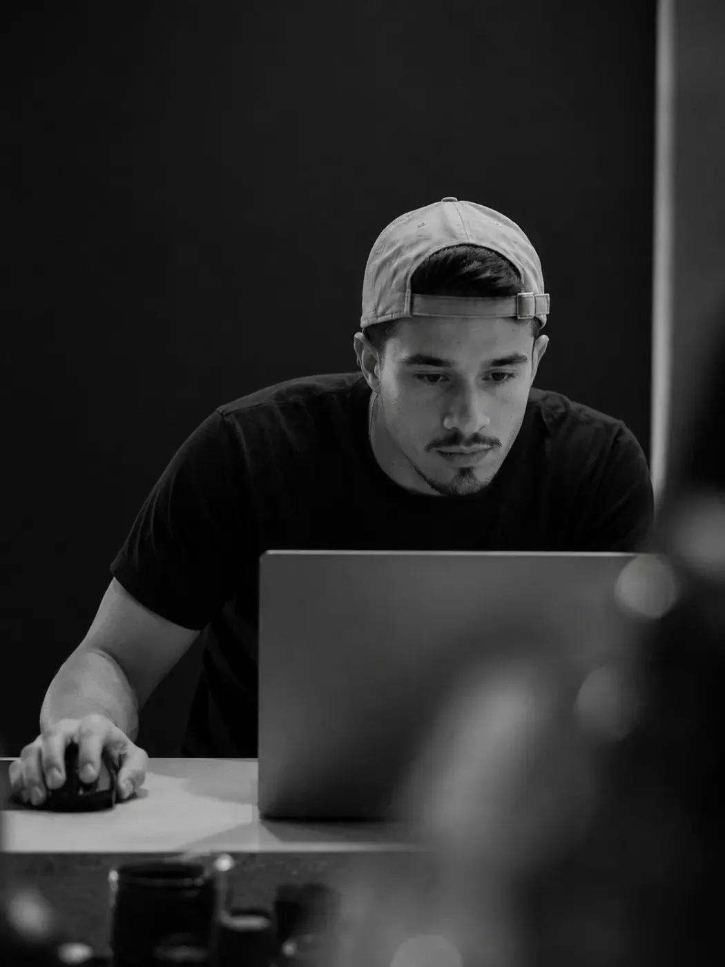 Retrato em preto e branco de Felipe trabalhando em um notebook.