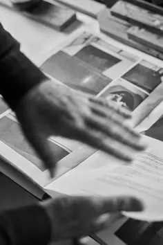 Mãos revisando material impresso e direção visual.